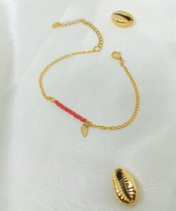 Photo d'un bracelet or et perles rouge avec cauri en or