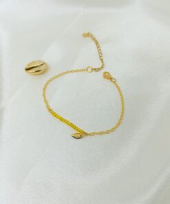 Photo d'un bracelet or et perles jaune avec cauri en or